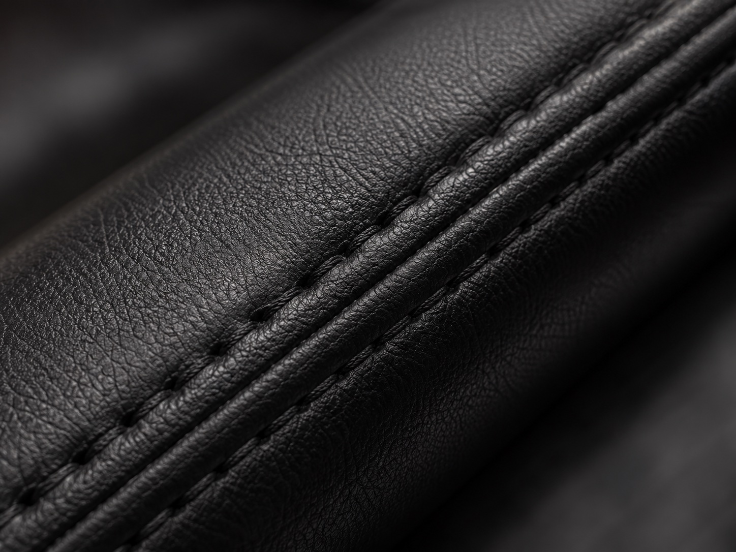 Reinforced stitching on black synthetic leather upholstery
