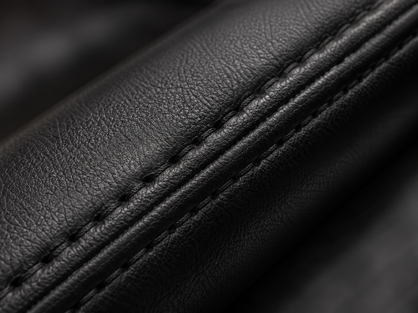 Reinforced stitching on black synthetic leather upholstery
